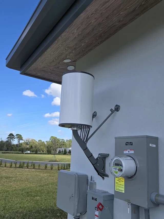 Outdoor wireless bridge antenna pole-mounted under the eave of a commercial building