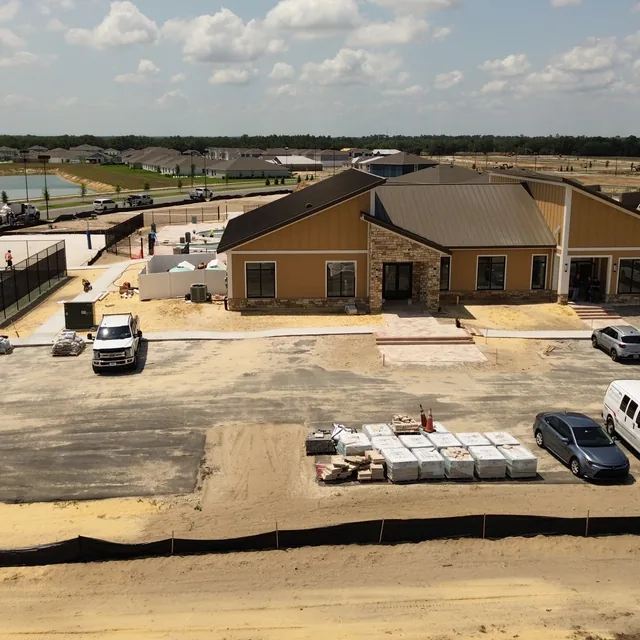 Aerial drone view of a community clubhouse under construction with pickleball courts and pool, Winter Haven, FL