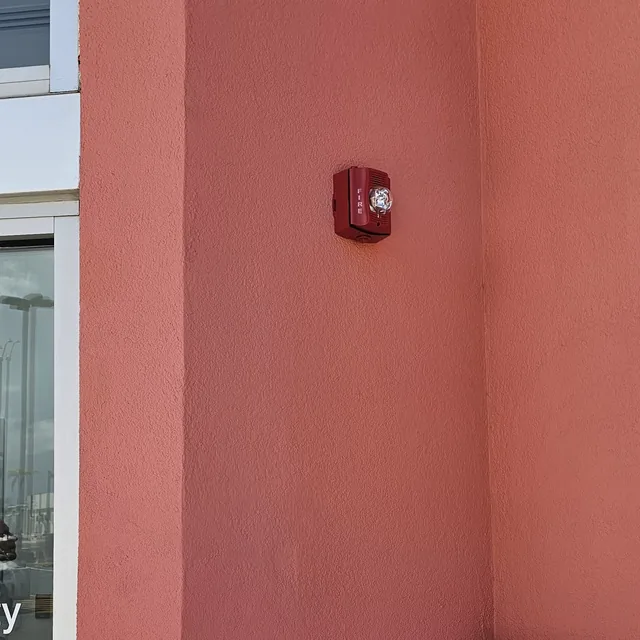 Weatherproof fire alarm horn strobe and door intercom station on a commercial building exterior, Kissimmee, FL