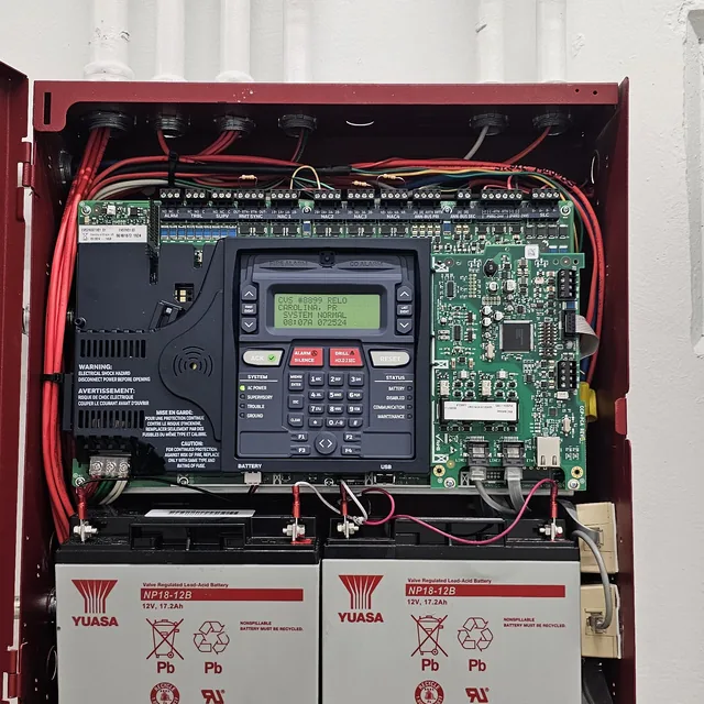 Open fire alarm control panel showing the addressable board, keypad display and sealed backup batteries