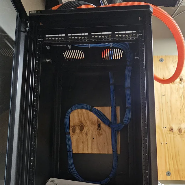 Open wall-mount network cabinet with a dressed Cat6 bundle and fiber innerduct entering from above