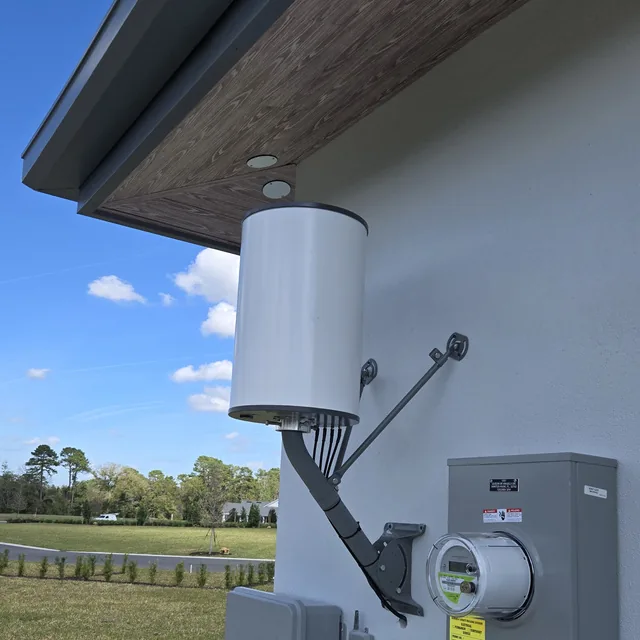 Outdoor wireless bridge antenna pole-mounted under the eave of a commercial building