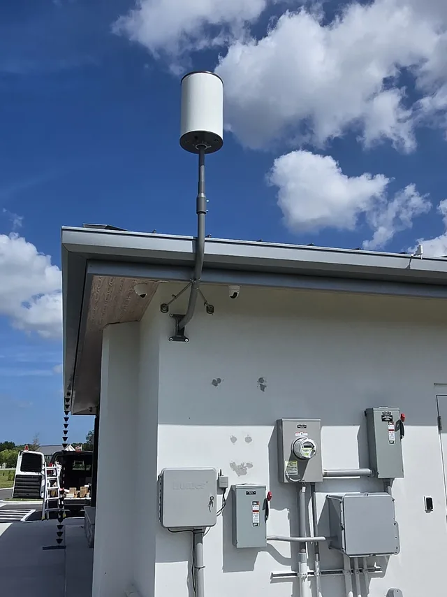 Commercial building exterior with a wireless antenna mast and dome security cameras